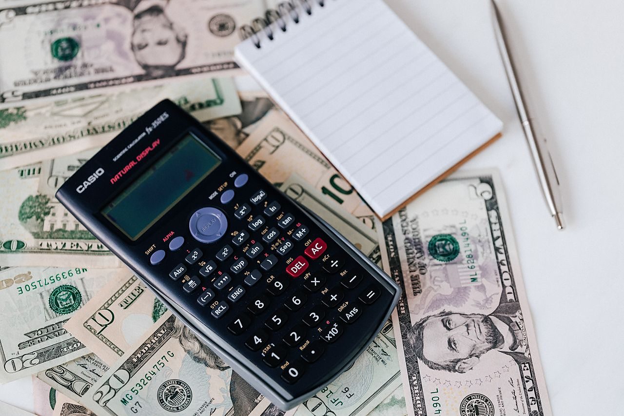 Calculating a funding services fee with a calculator and notepad
