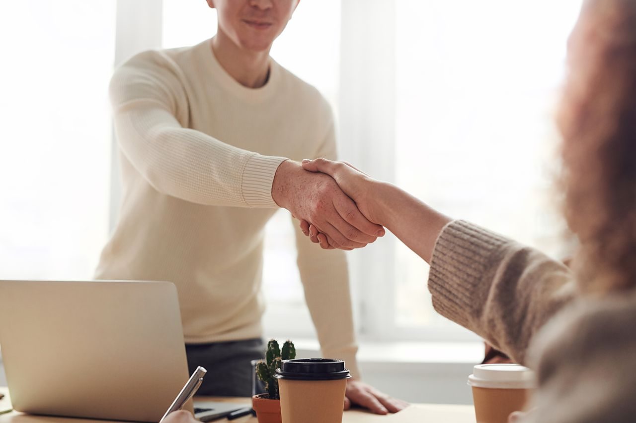 A funding agreement handshake across a desk
